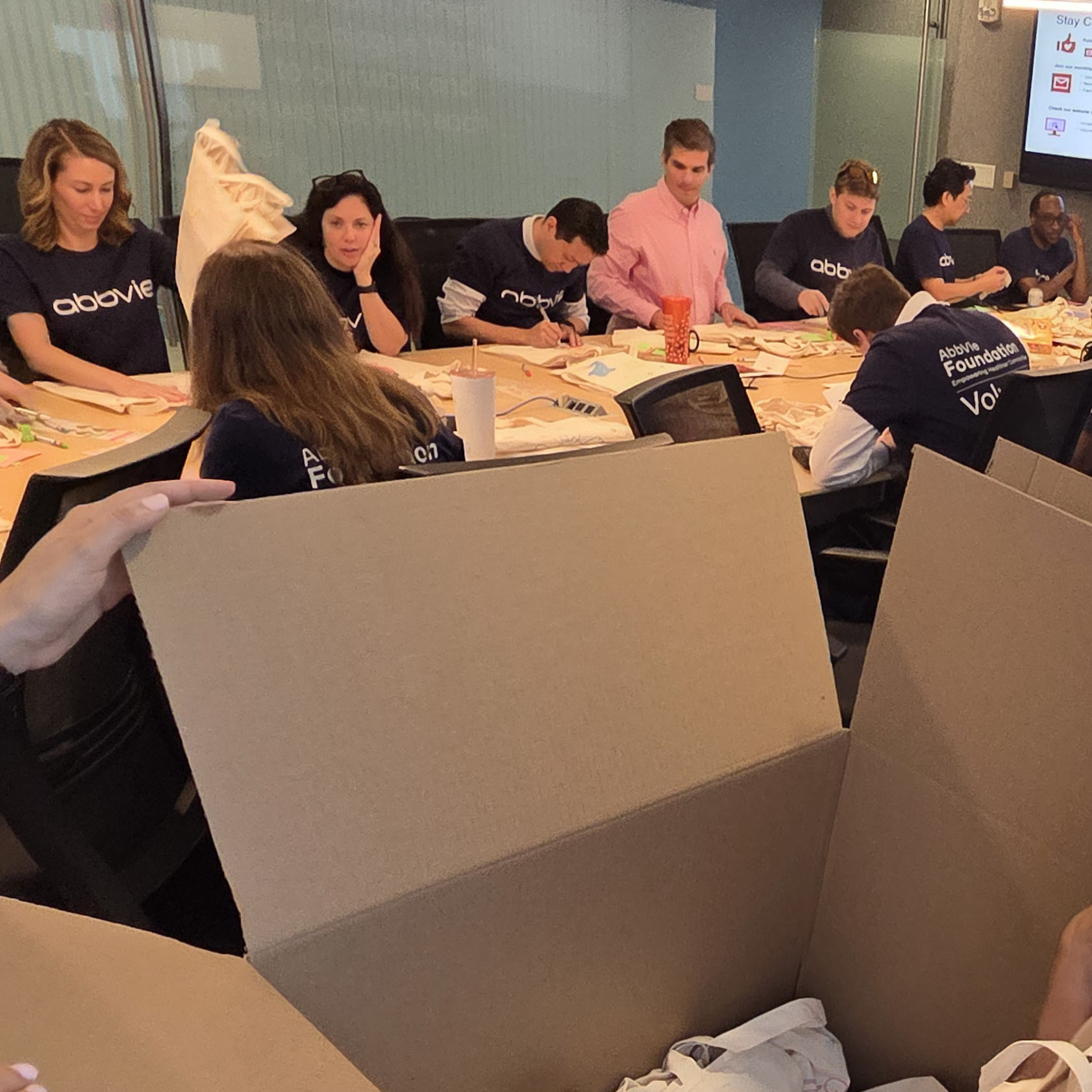 AbbVie employees gather around a conference table while decorating tote bags and assembling care kits for families staying at Ronald McDonald House Washington DC. The volunteer event was part of the AbbVie Foundation's Week of Possibilities, supporting families at the Washington DC and Northern Virginia Houses.