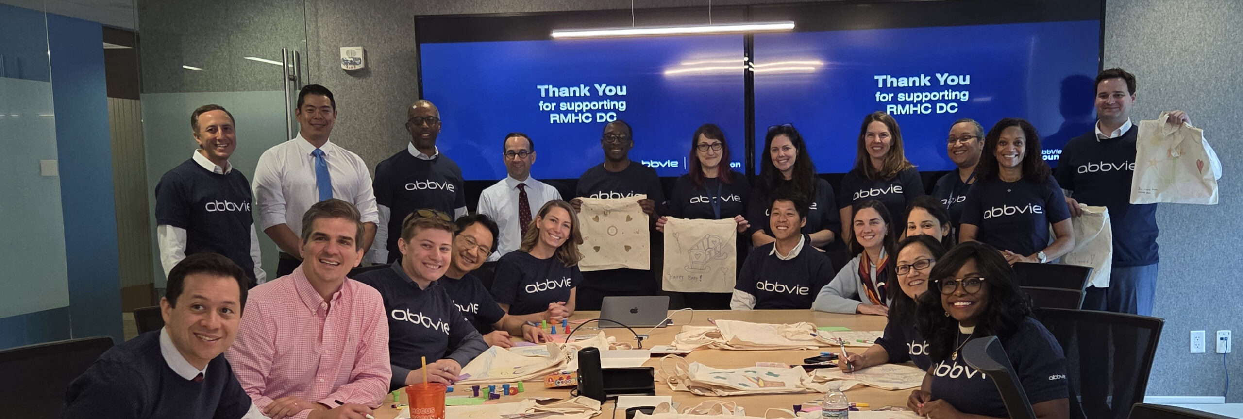 AbbVie employees gather around a conference table while decorating tote bags and assembling care kits for families staying at Ronald McDonald House Washington DC. The volunteer event was part of the AbbVie Foundation's Week of Possibilities, supporting families at the Washington DC and Northern Virginia Houses.